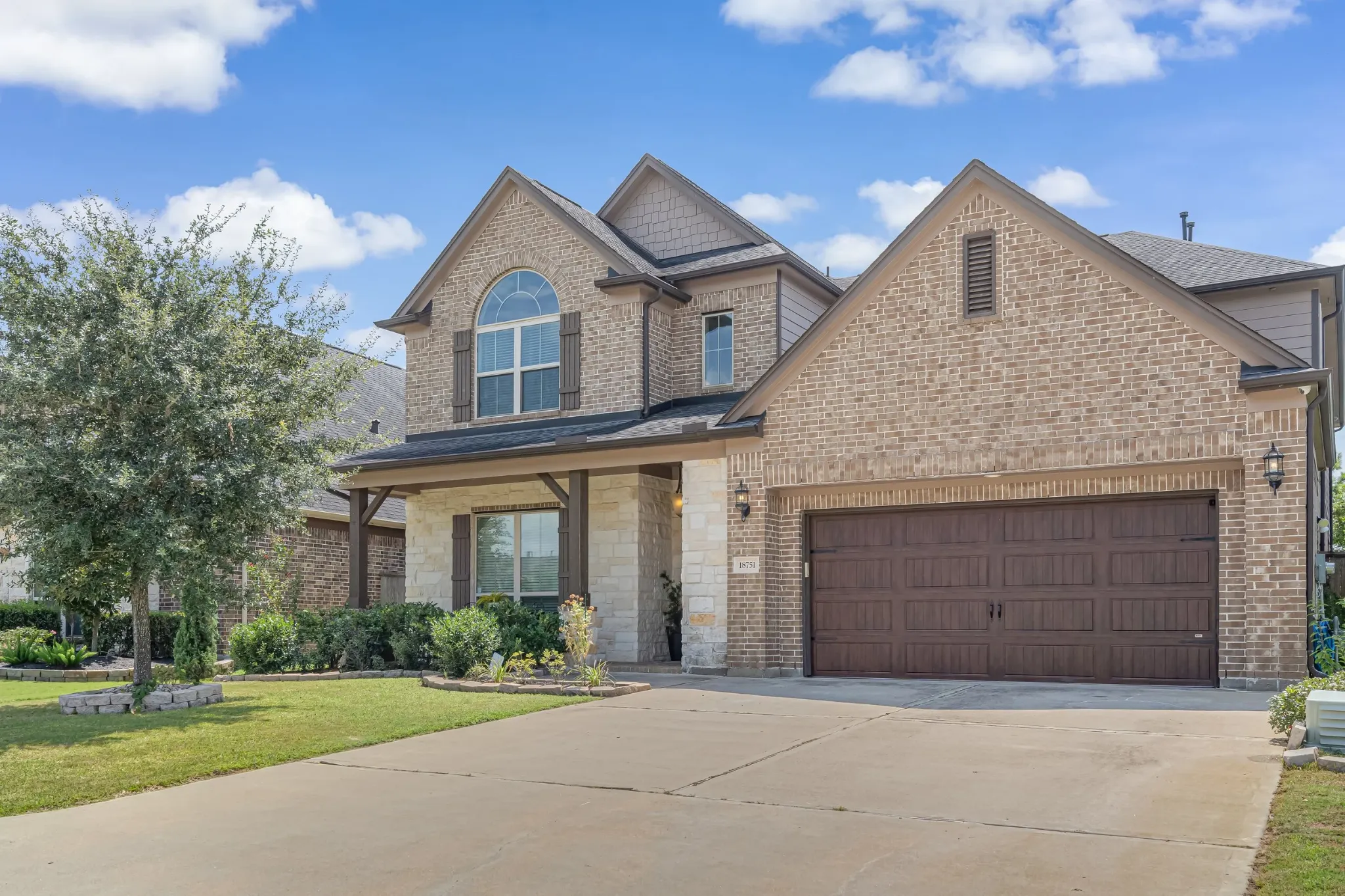 Two-story brick residence with a broad driveway and landscaped front yard