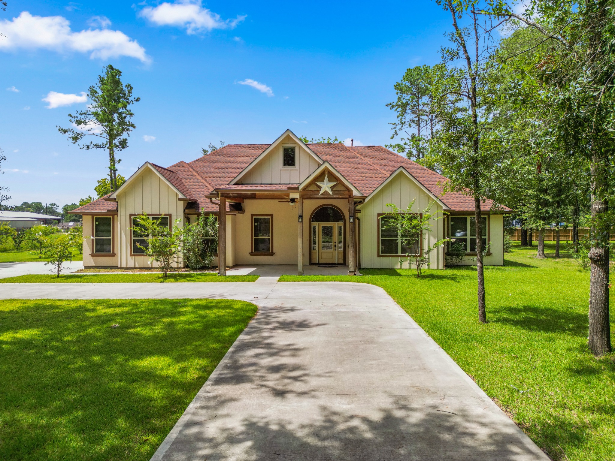 A country home with a long driveway, front porch, and green lawn