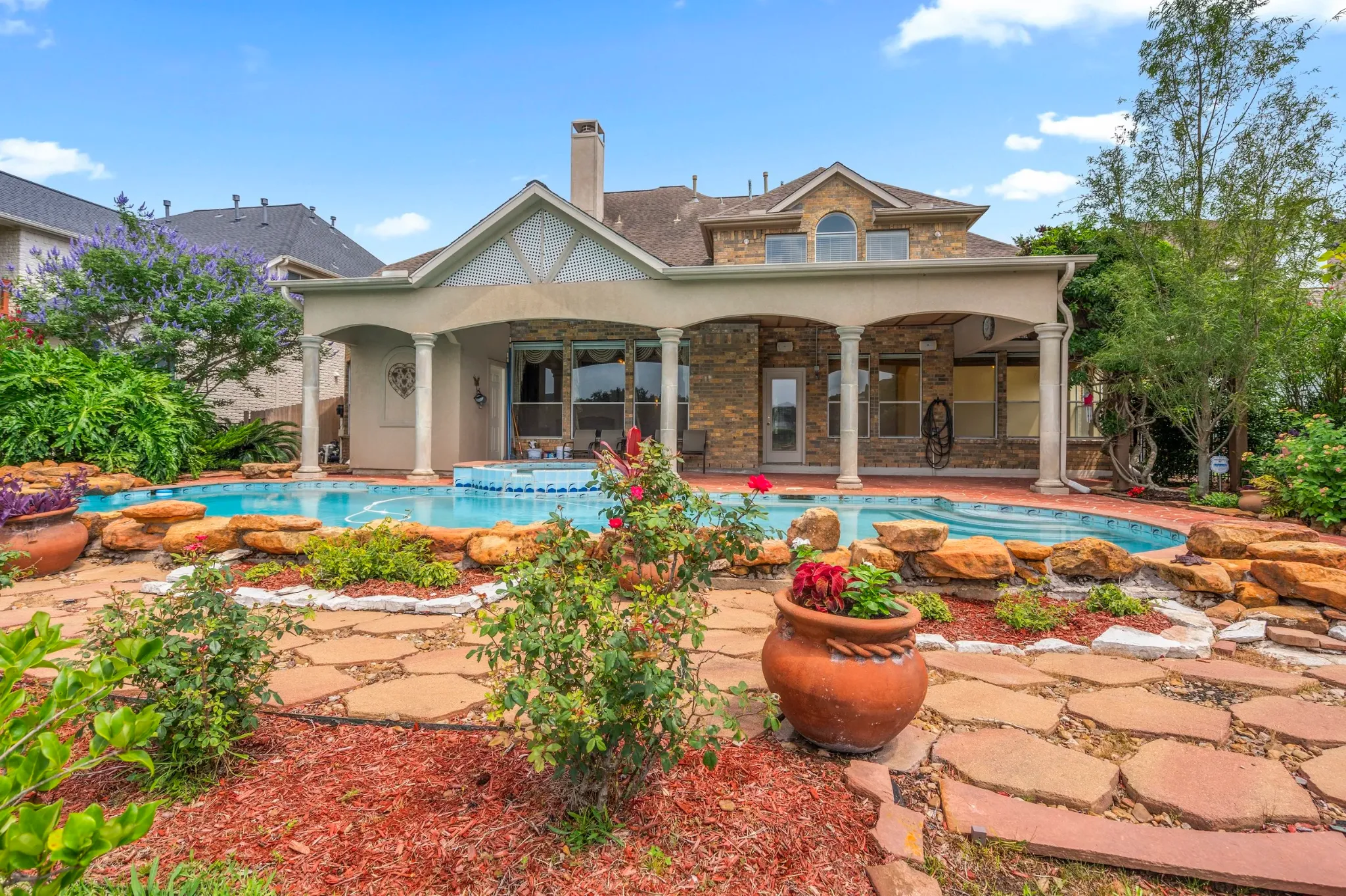 Landscaped garden and pool behind a large brick residence