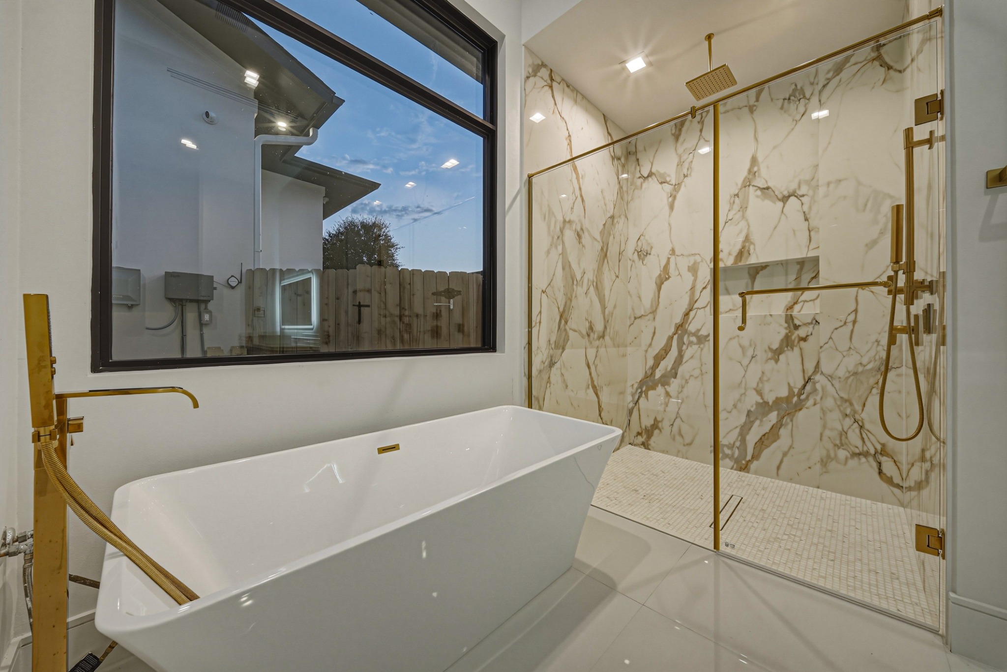 Bathroom with marble walls, freestanding tub, and brass fixtures