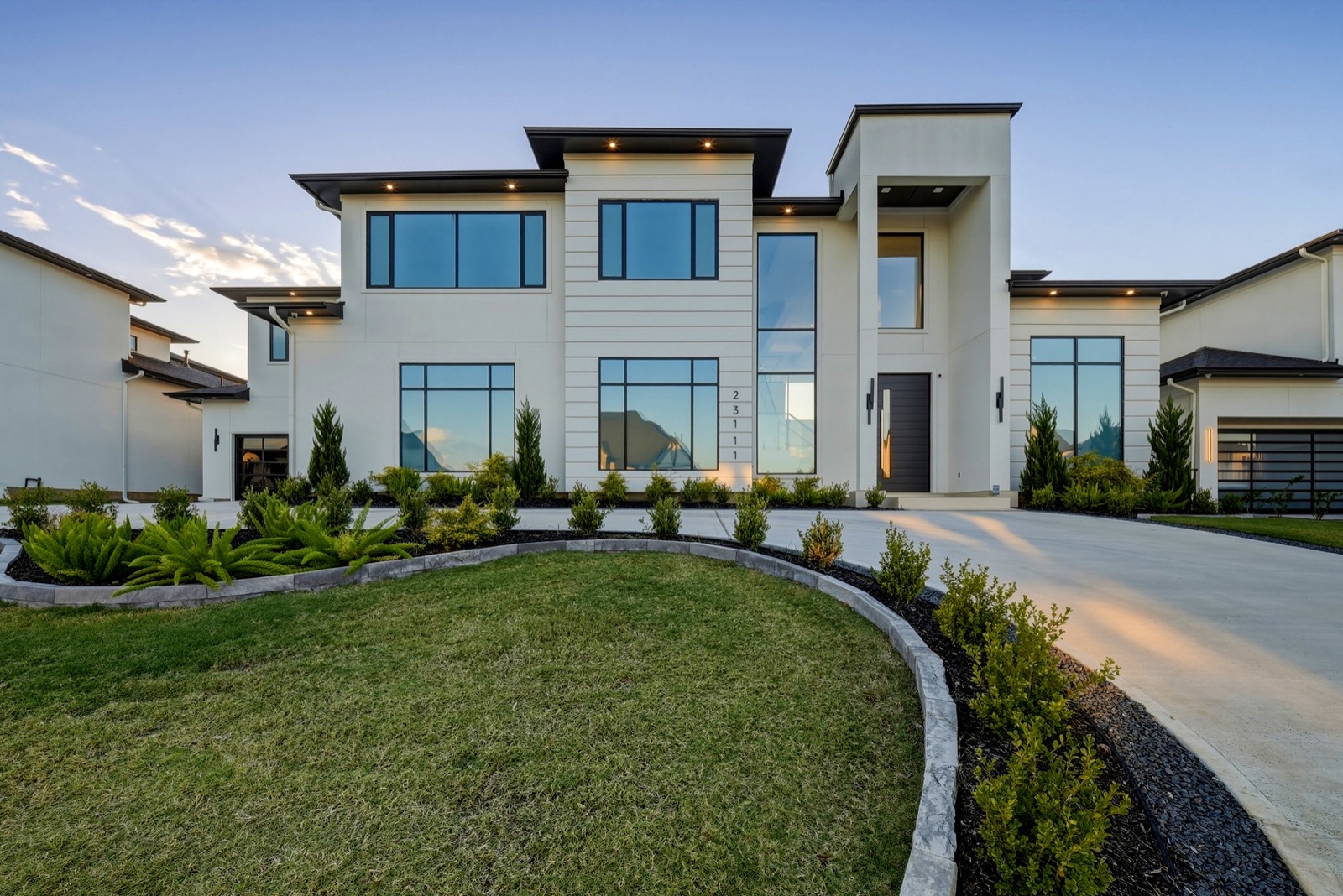 Modern white home at dusk, photographed from the driveway