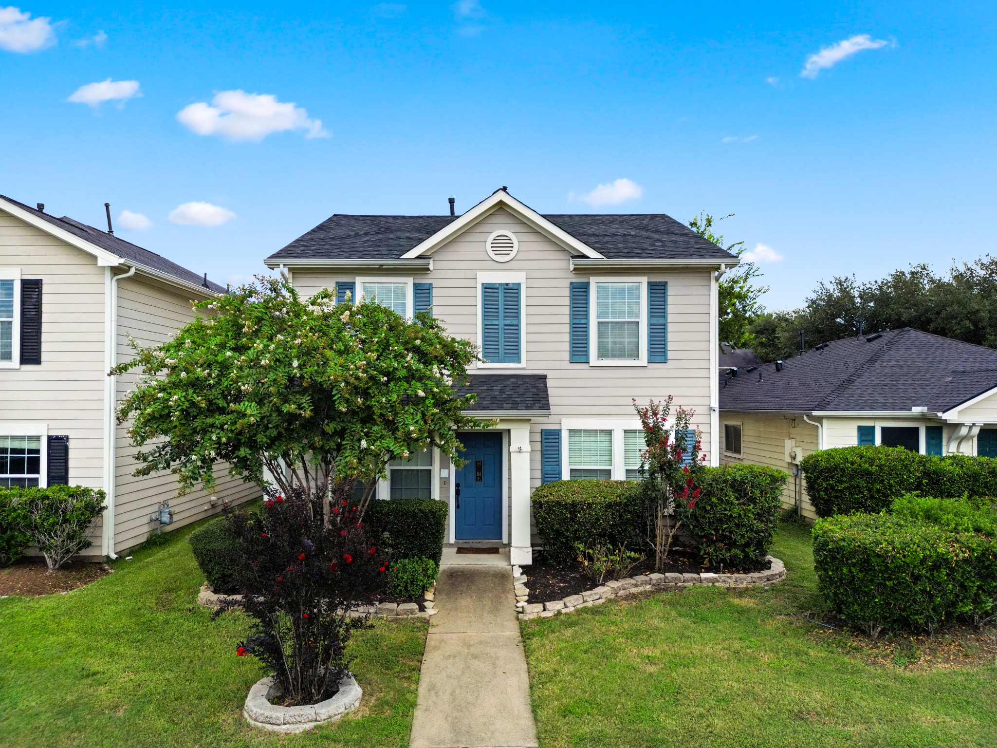 Two-story home with a blue front door and landscaped front yard