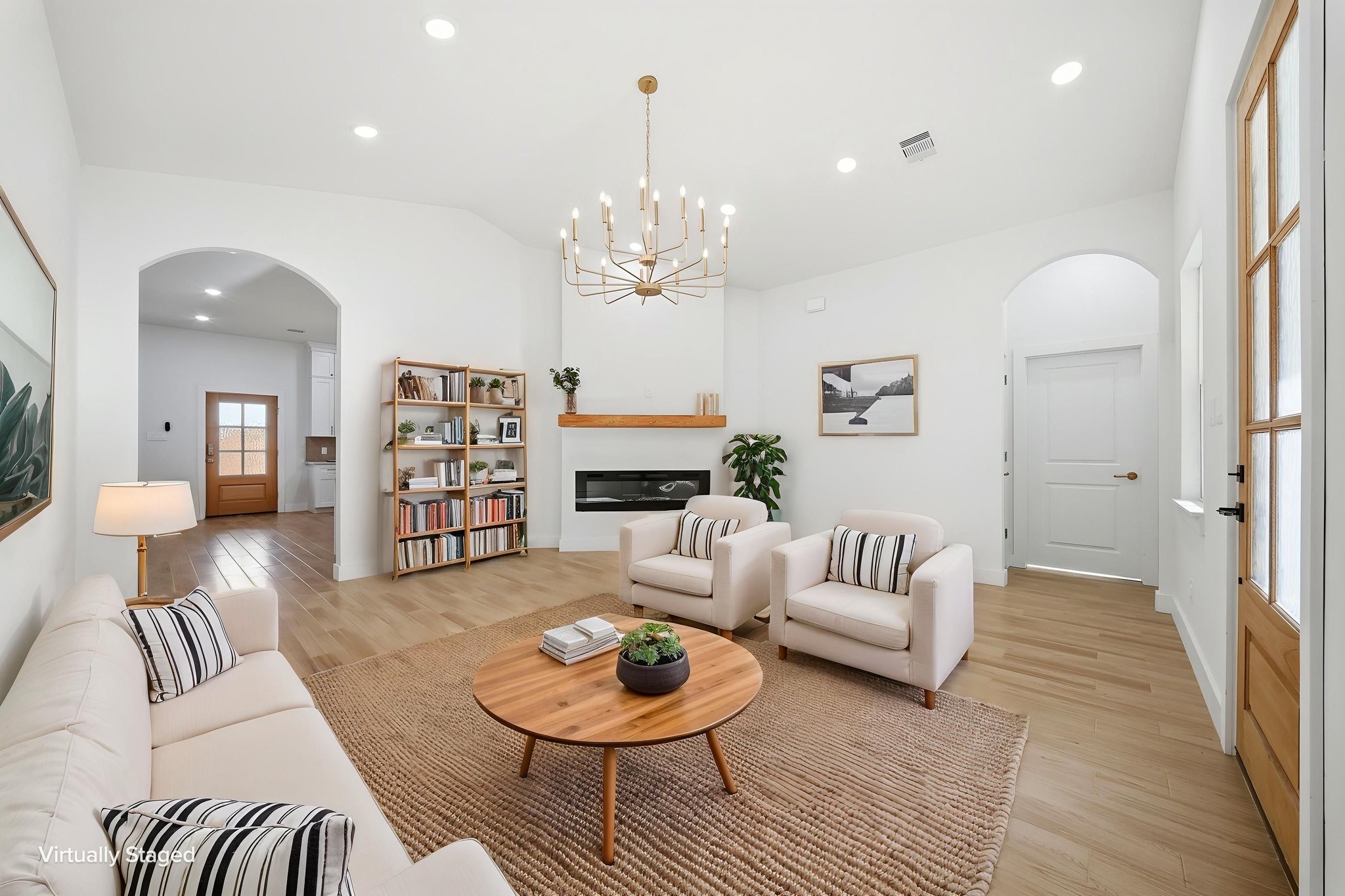 Bright living room with high white ceiling, chandelier, and pale seating