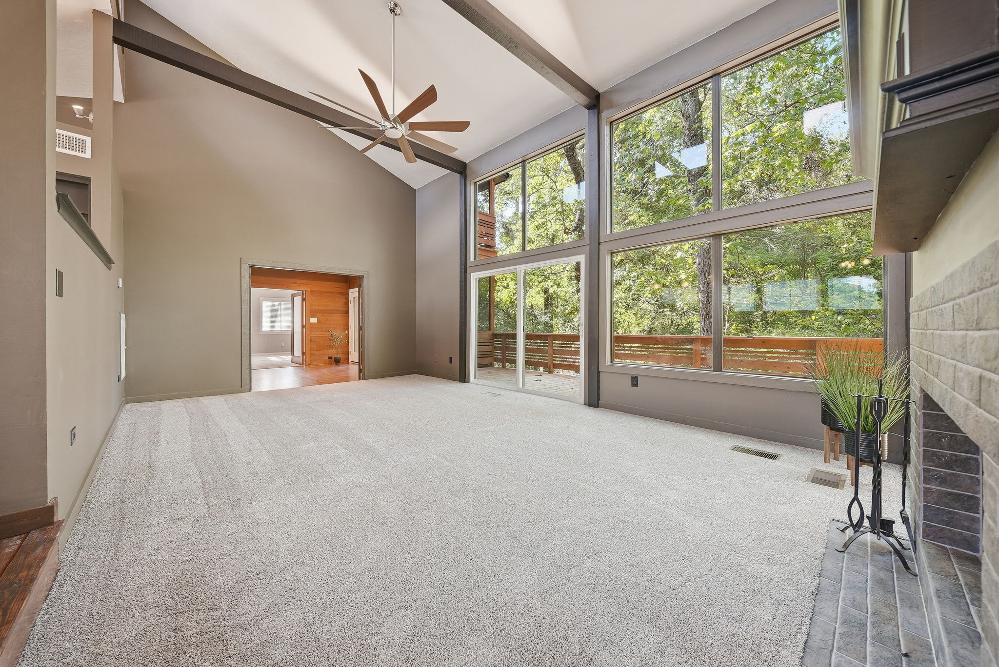 Tall empty room with exposed beams and large windows overlooking trees