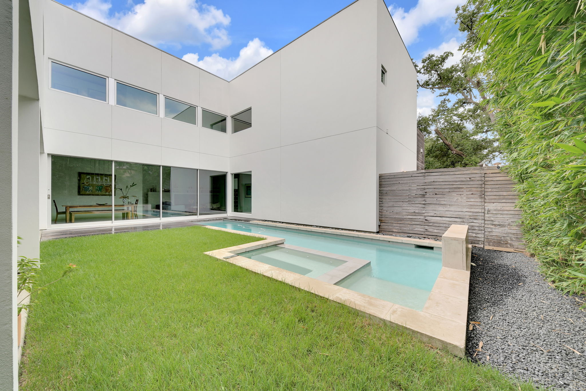 White modern residence with a grassy courtyard and narrow pool