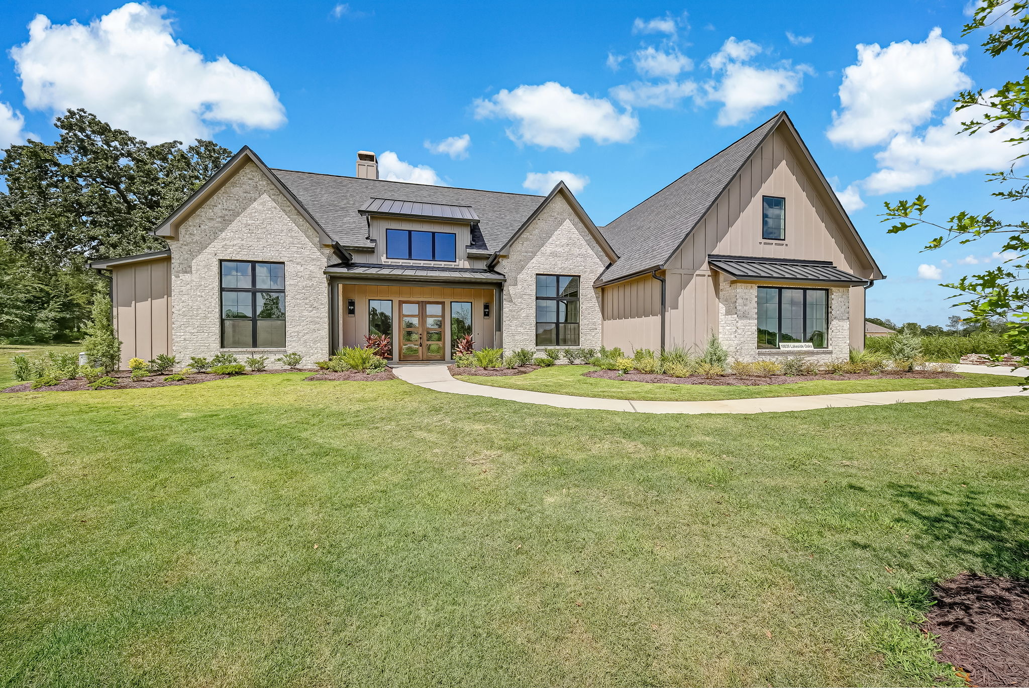 Stone and brick home behind a broad lawn under a blue sky