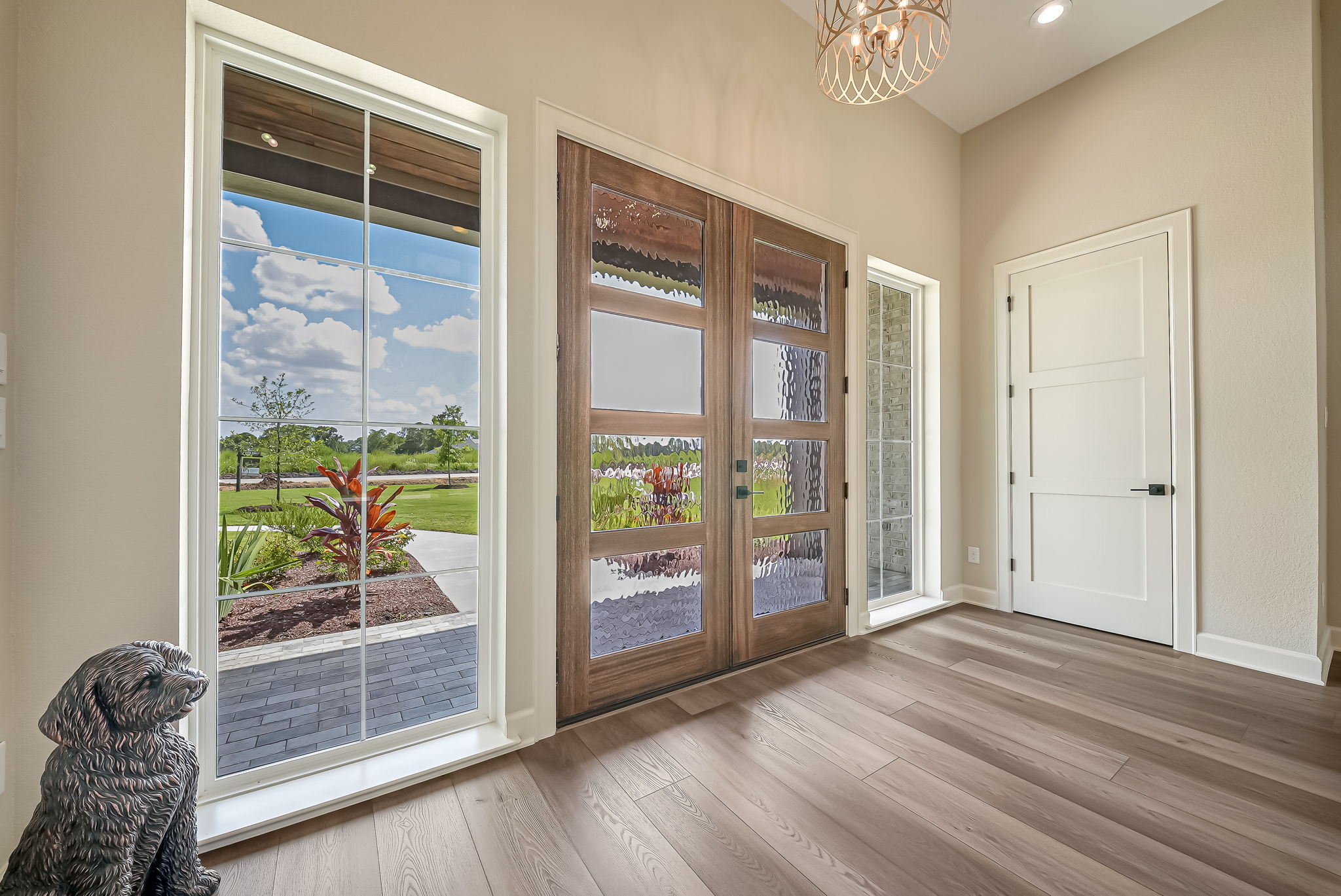Wood-framed entry doors and windows opening toward a landscaped yard