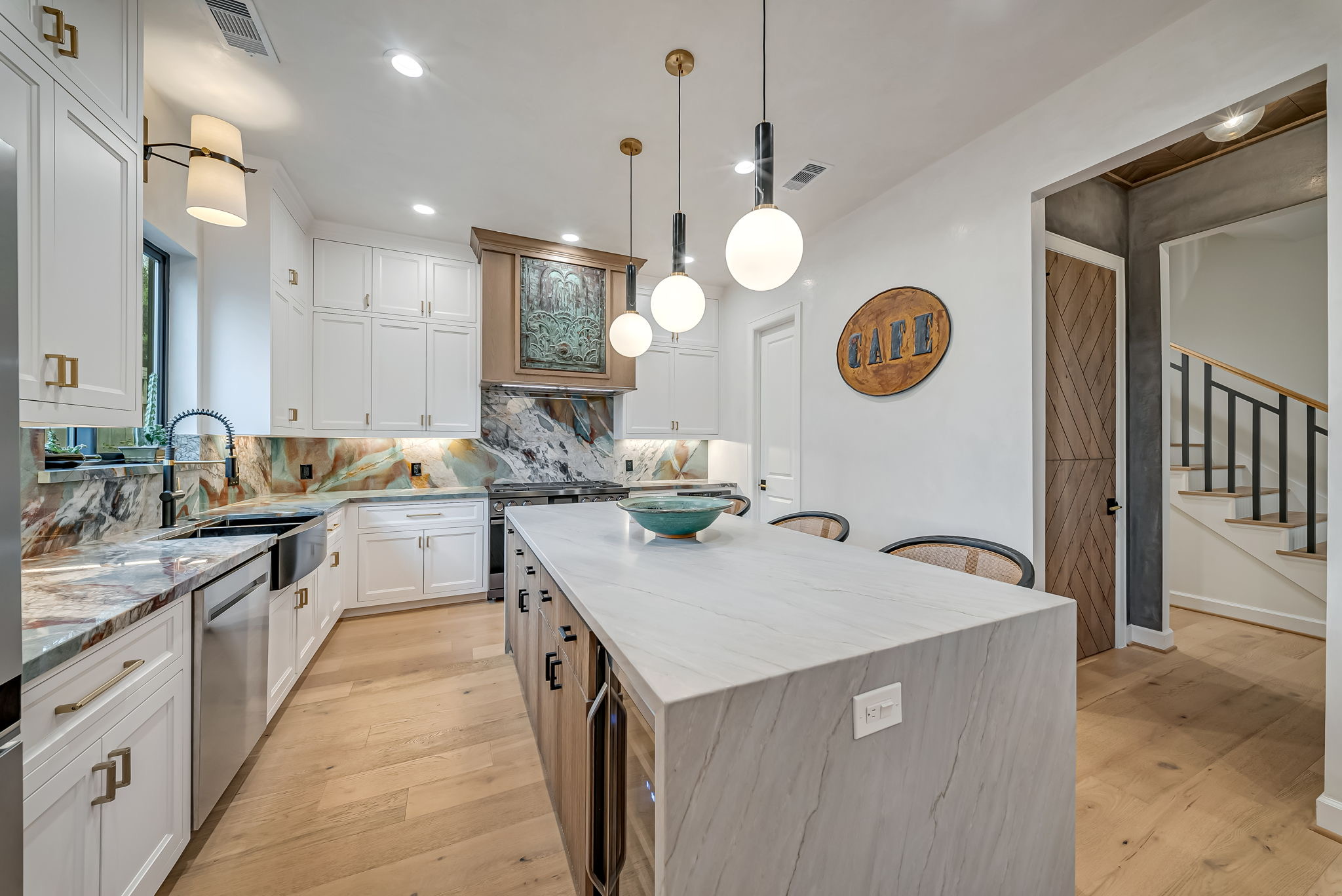Bright kitchen with white island, pendant lights, and a tiled backsplash
