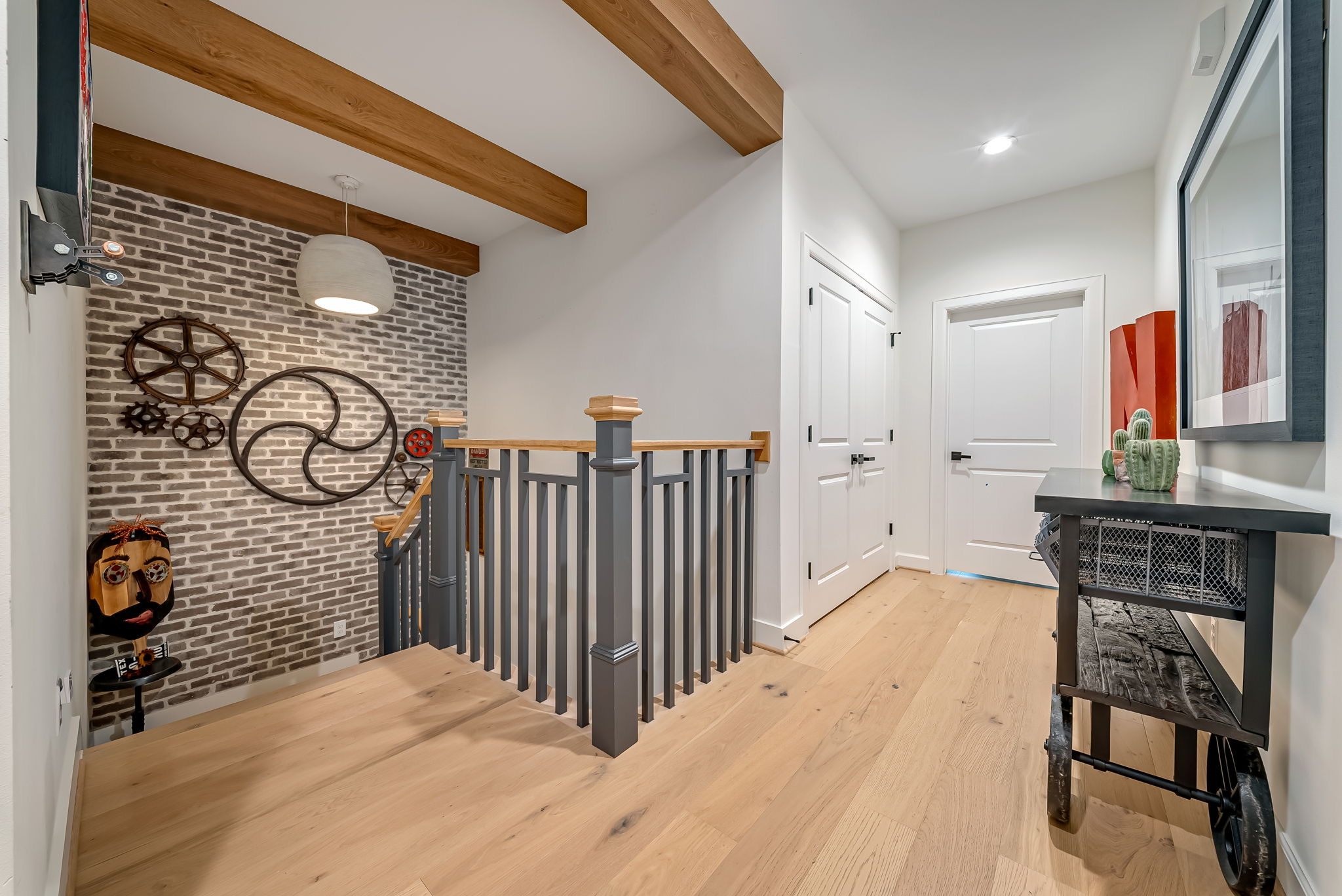 Upper floor walkway with wood beams and an iron stair railing