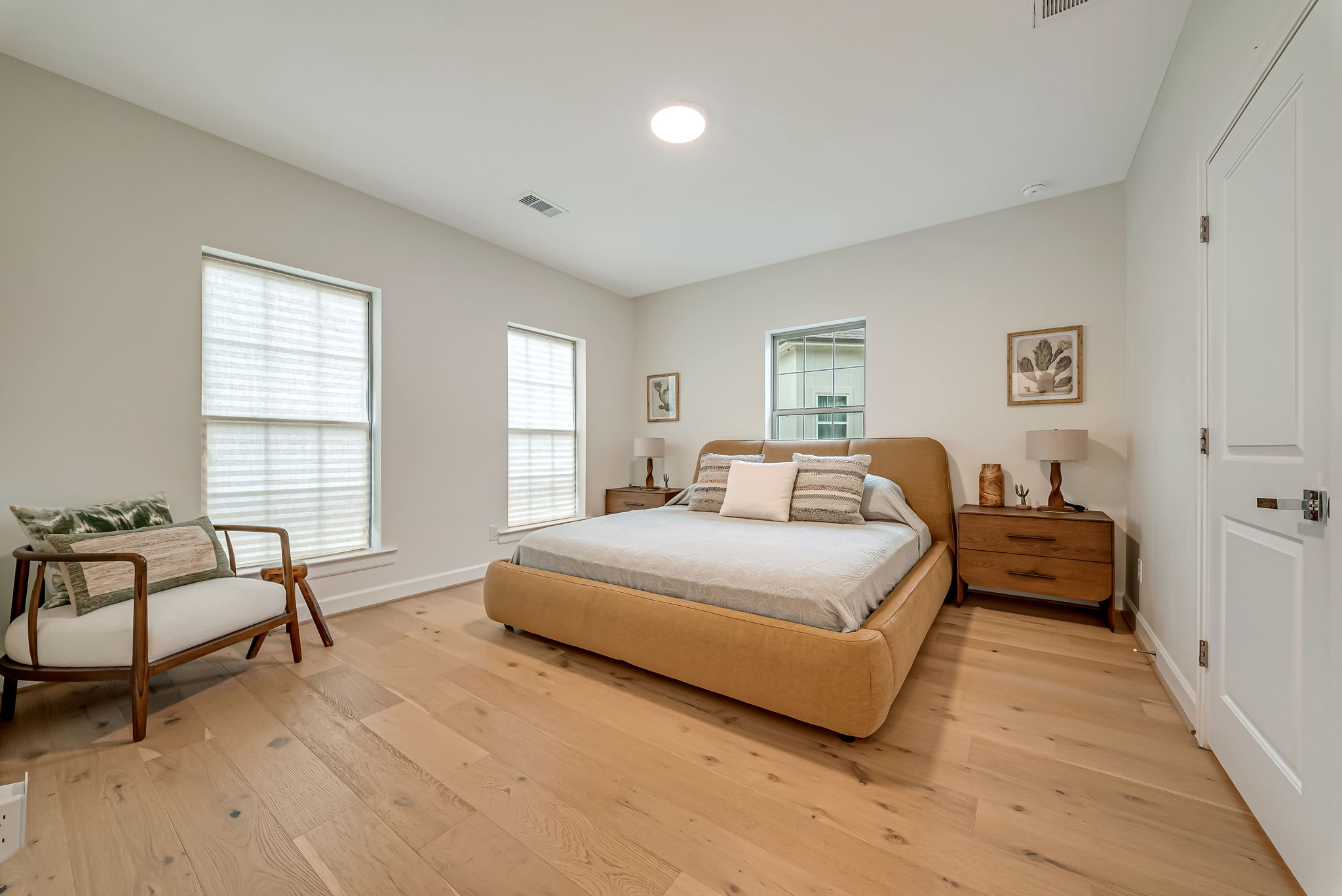 Neutral bedroom with wood bed and two sunlit windows