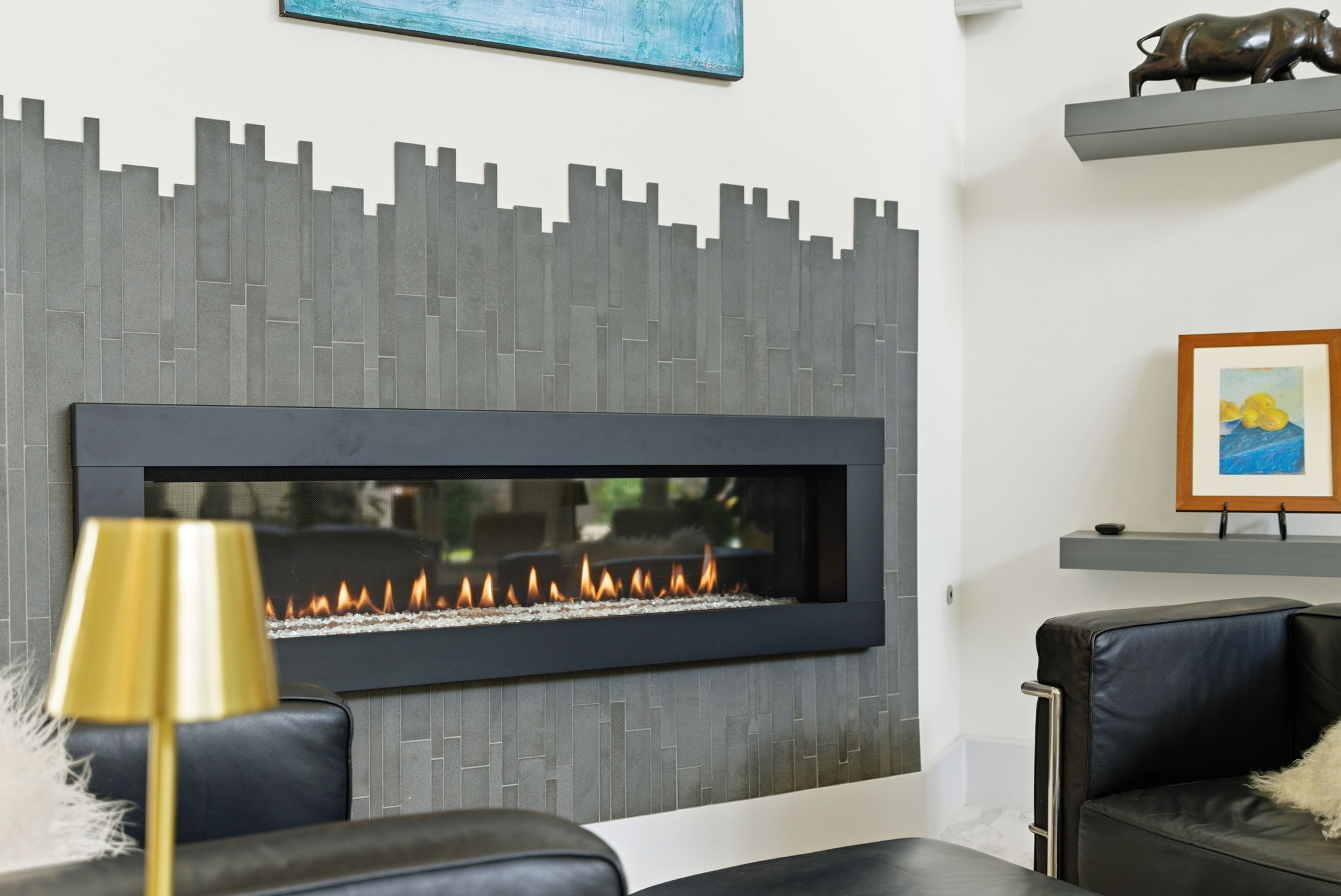 Contemporary fireplace wall with dark seating and gold lamps