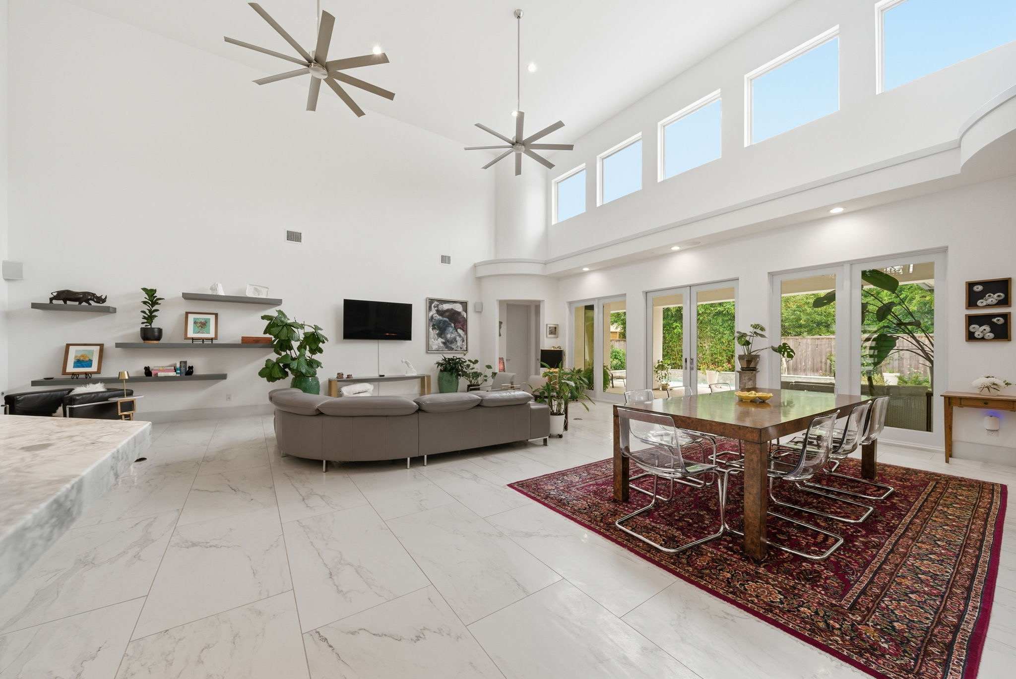 Large white living room with high ceiling and windows facing the garden
