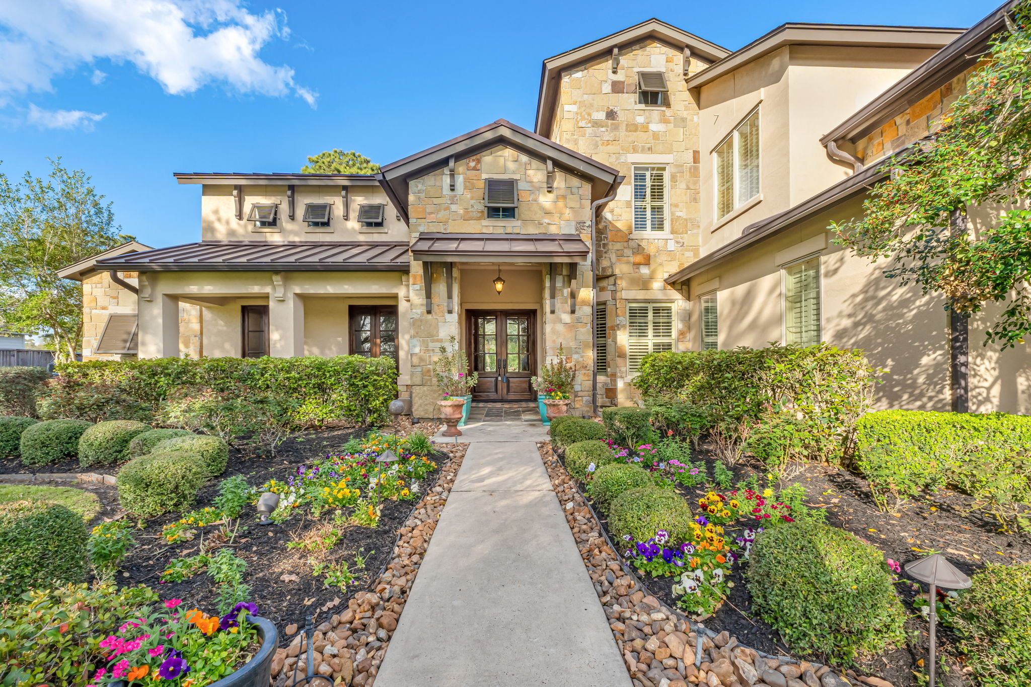 Stone residence framed by hedges and a landscaped front walk