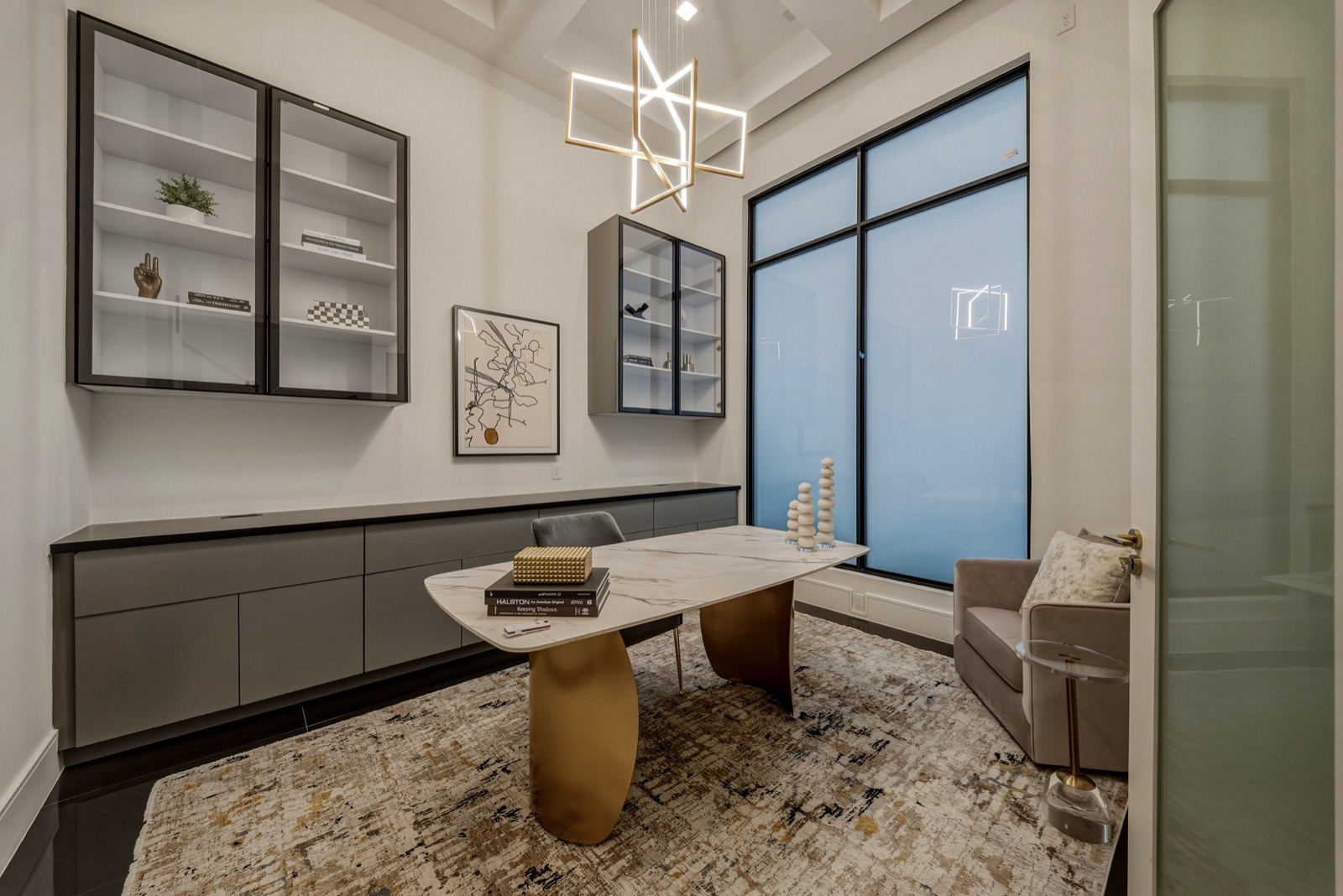 Modern study with dark cabinetry, a desk, and large windows