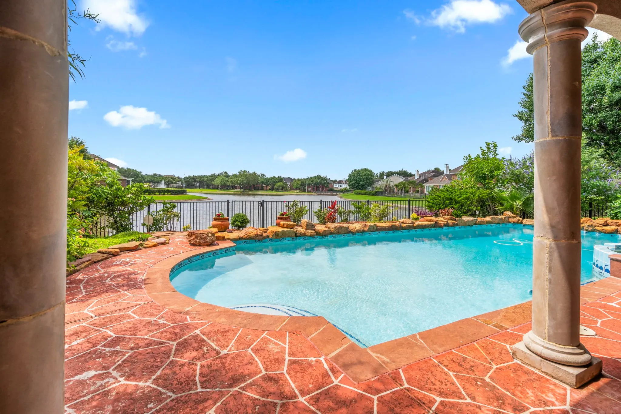 Curved outdoor pool overlooking a lake beneath a clear blue sky