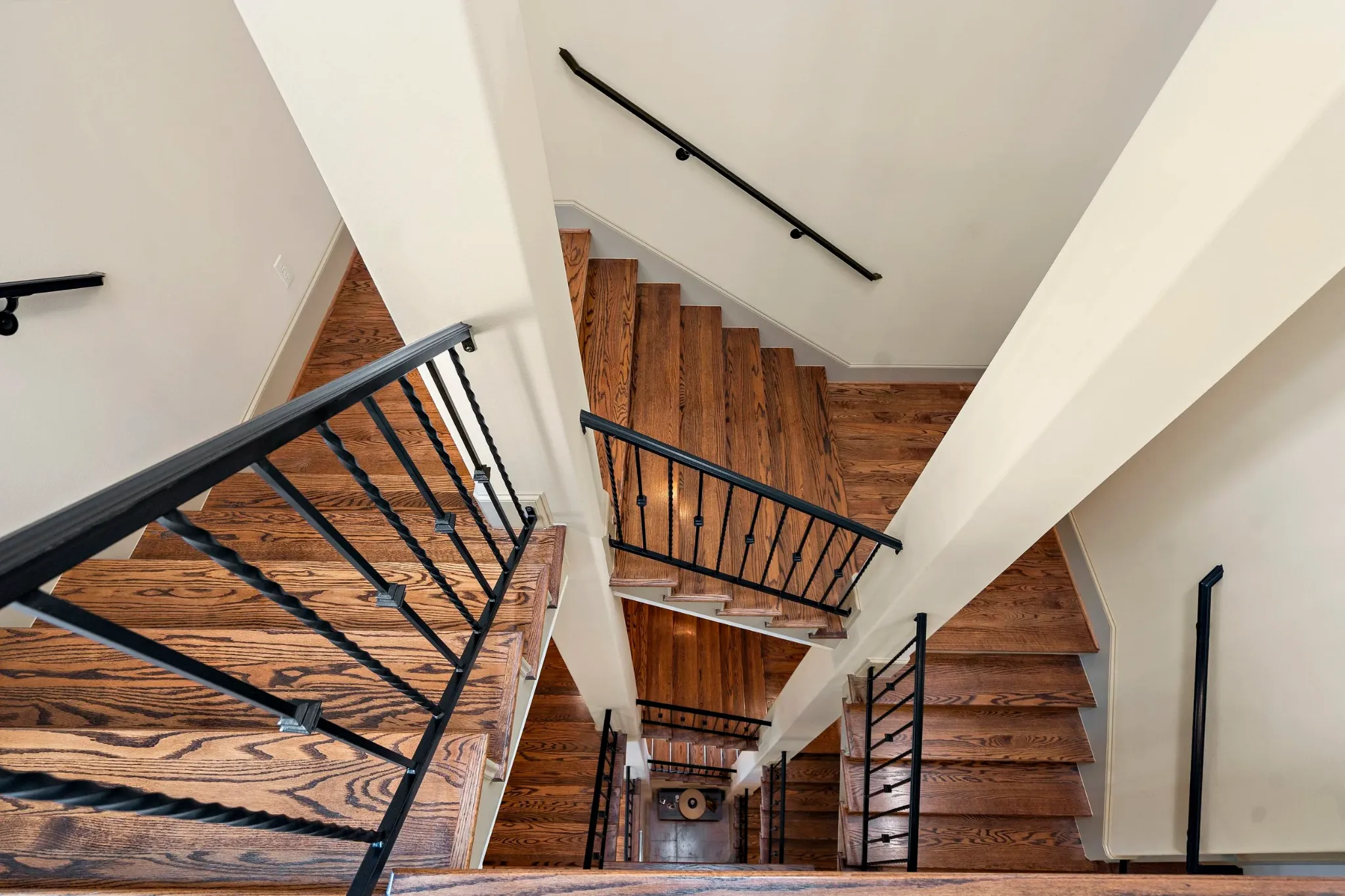 View down a wood staircase with dark iron railings