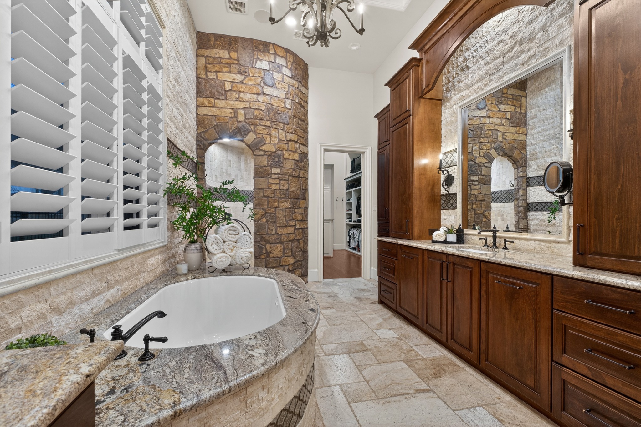 Bathroom with a stone wall, soaking tub, and wood cabinetry
