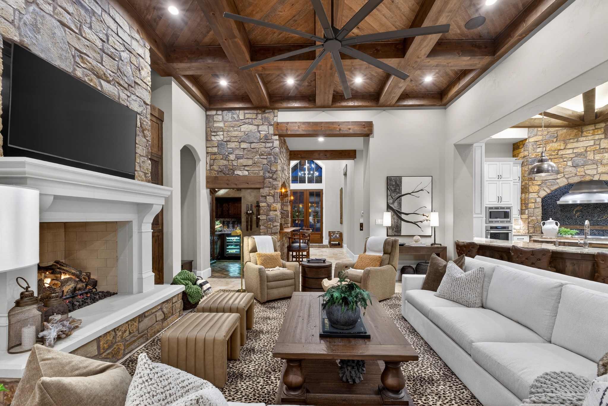 Great room with timber ceiling, stone fireplace, and tall windows
