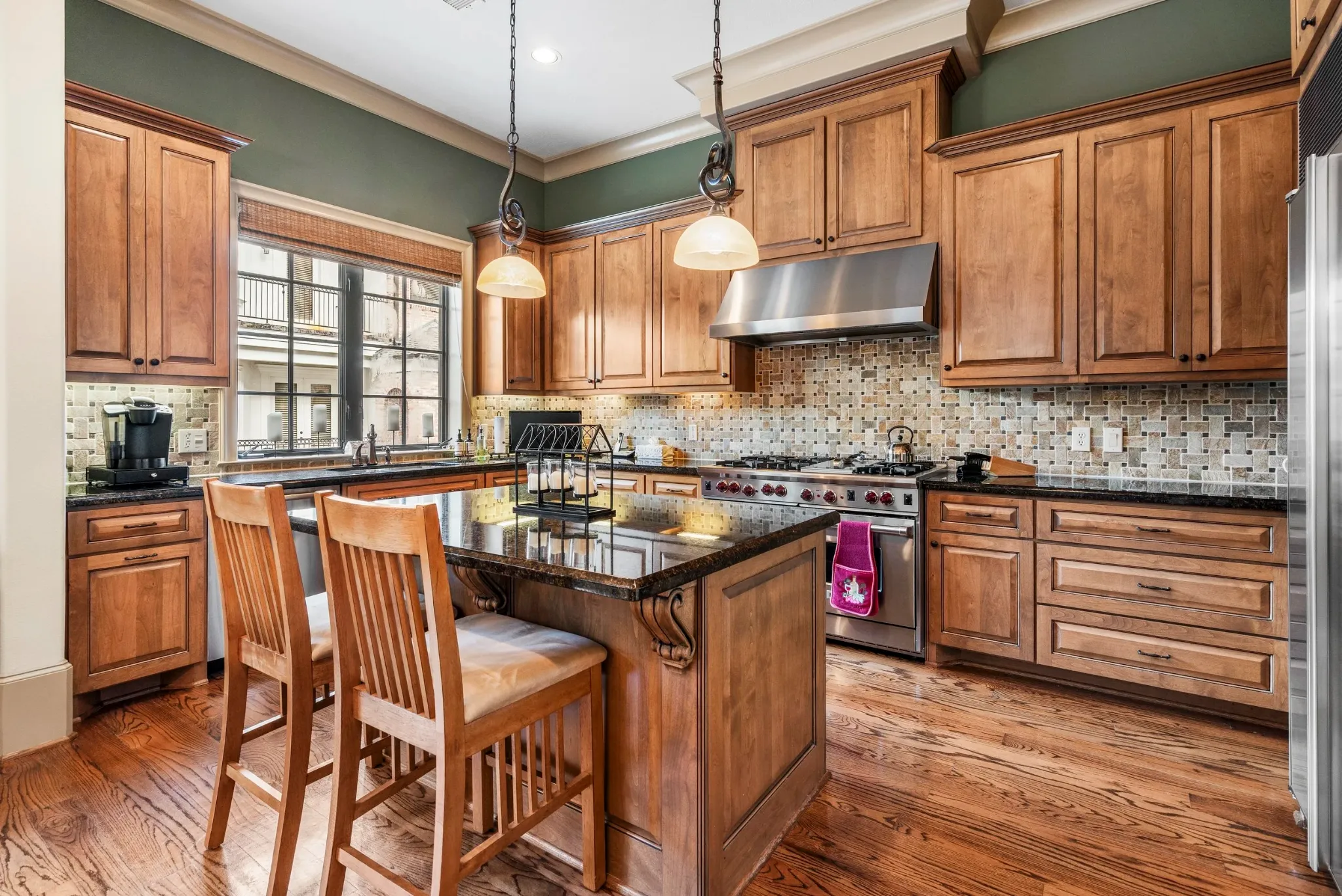 Kitchen with wood cabinetry, a central island, and pendant lights