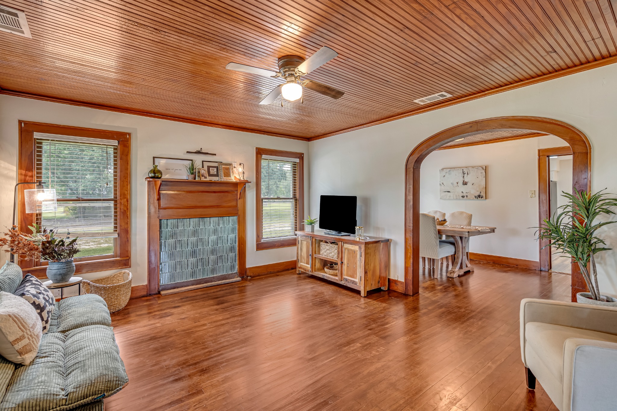 Warm living room with wood ceiling, fireplace, and arched opening