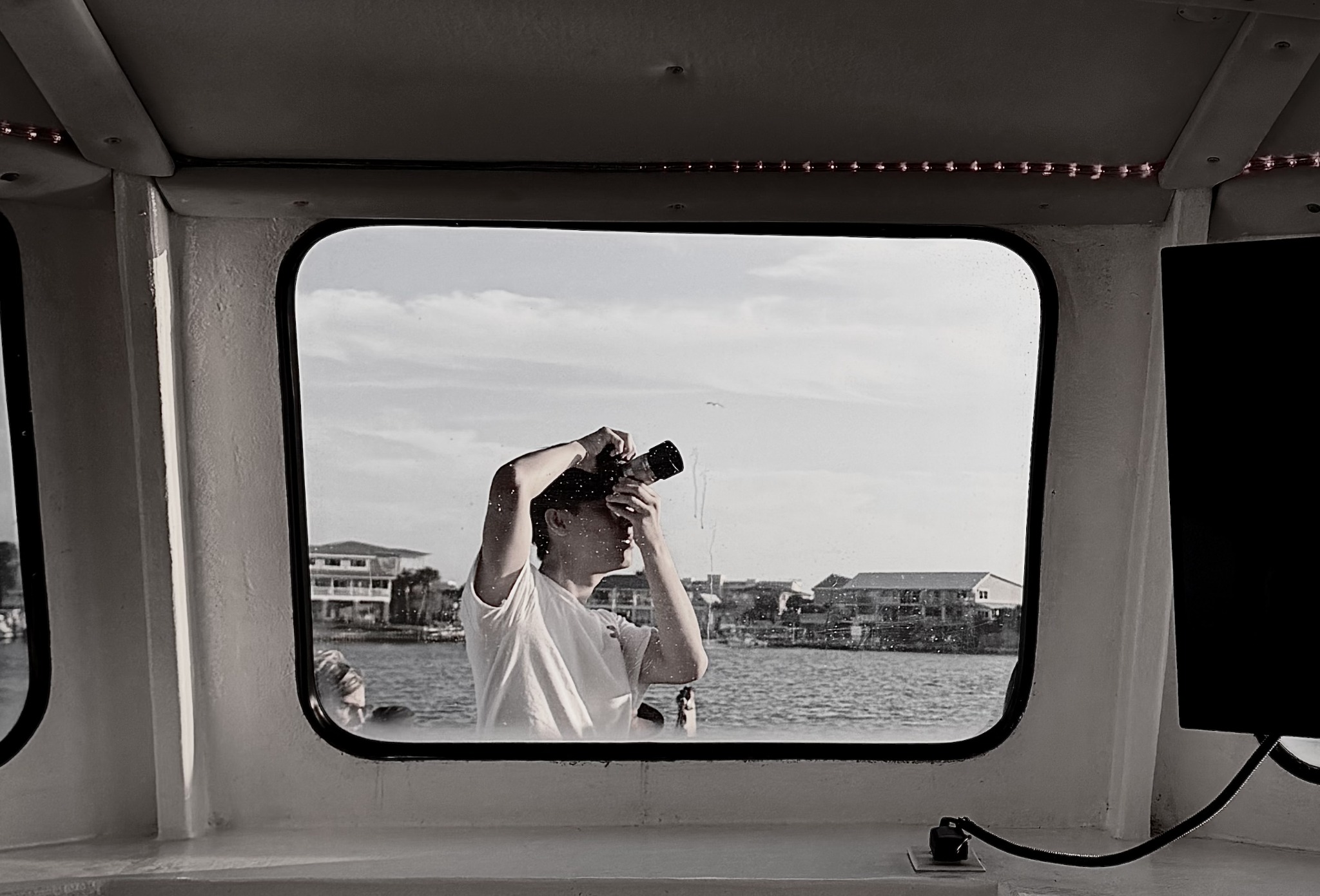 Sam Zhou photographing from outside a window by the water