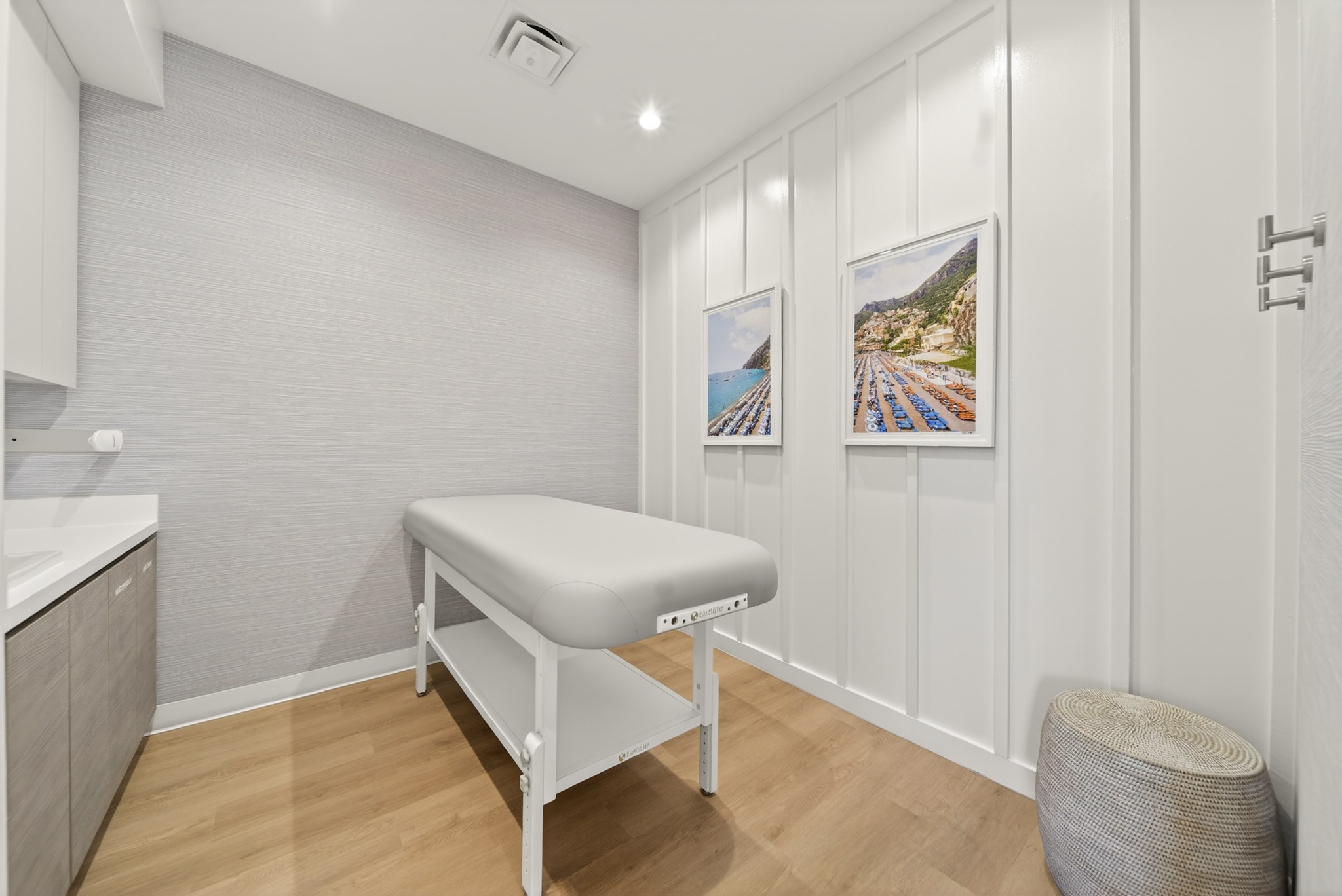 A treatment room with a bed and white wall panels
